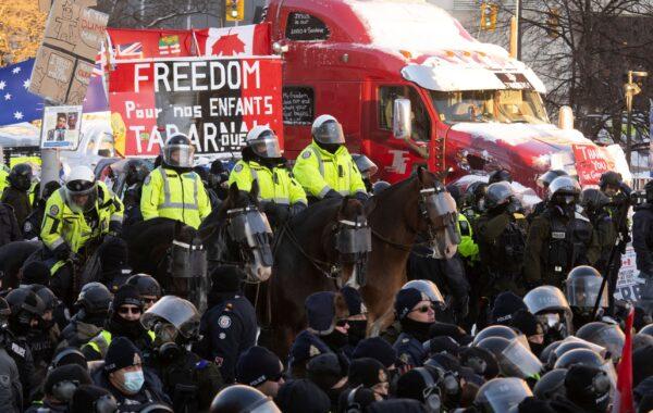 A mounted police unit lines up behind public order units on foot to clear away protesters from downtown Ottawa on Feb. 18, 2022. (The Canadian Press/Adrian Wyld)