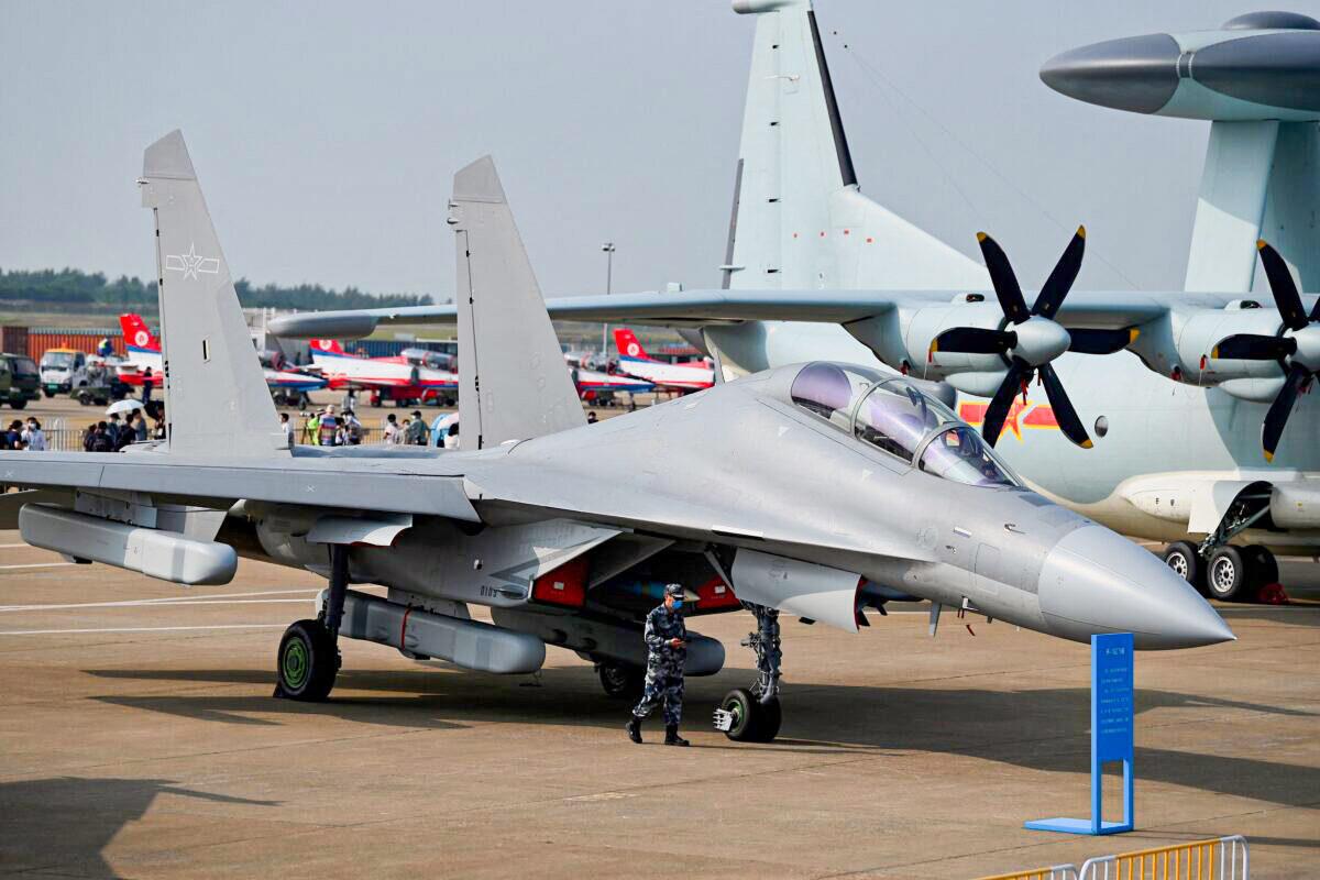 A military personnel walks past Shenyang Aircraft Corporation's J-16 multirole strike fighter for the People's Liberation Army Air Force (PLAAF) at the 13th China International Aviation and Aerospace Exhibition in Zhuhai, southern China's Guangdong Province, on Sept. 28, 2021. (Noel Celis/AFP via Getty Images)
