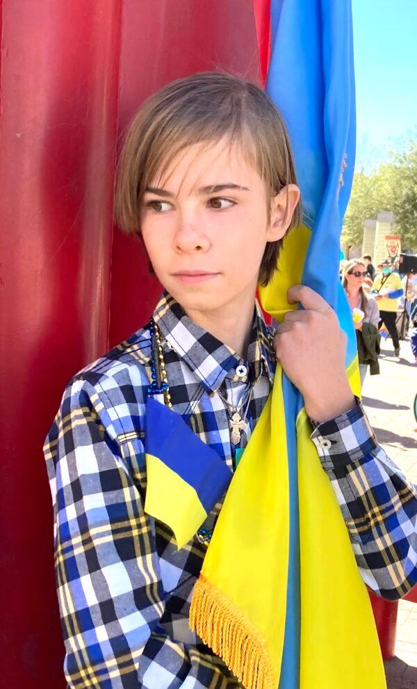  Maximilian Lautaire, 12, holds the flag of Ukraine during an anti-war rally in Tucson, Ariz., on March 6. Lautaire attended the protest to call on Russia to put an end to its invasion of Ukraine. (Allan Stein/The Epoch Times)
