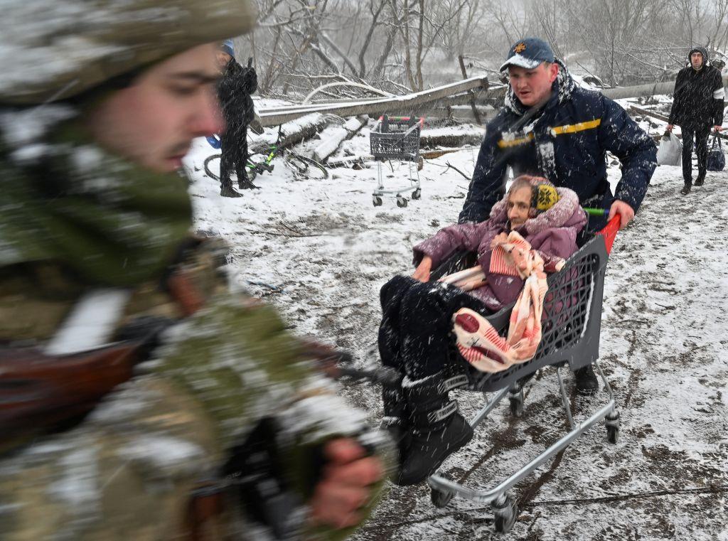 A rescuer pushes a cart with an elderly woman during the evacuation by civilians from the city of Irpin, northwest of Kyiv, on March 8, 2022. (Sergei Supinsky/AFP via Getty Images)