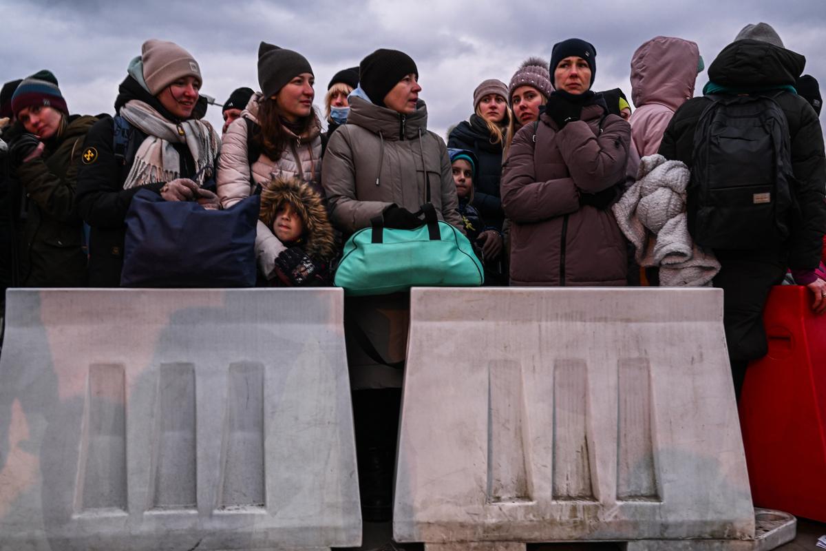 People who fled the war in Ukraine wait in line to board a bus behind removable barriers as Police officers and Polish Territorial defense soldiers help to manage the crowd after crossing the Polish Ukrainian border in Medyka, Poland, on March 8, 2022. (Omar Marques/Getty Images)