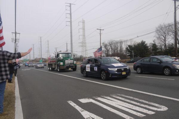 Trucks and vehicles of the New Jersey convoy on a highway in Edison, New Jersey, on March 5, 2022. People on the roadside wave American flags in support of the convoy. (Ella Kietlinska/The Epoch Times)