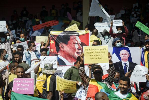 Protesters hold the portraits of China's President Xi Jinping (C) and Russia's President Vladimir Putin (R) among their messages during a massive rally to rail against the United States imposing restrictions on economic and security assistance over the conflict in the Tigray region at Addis Ababa soccer stadium in Addis Ababa, Ethiopia, on May 30, 2021. (Amanuel Sileshi/AFP via Getty Images)