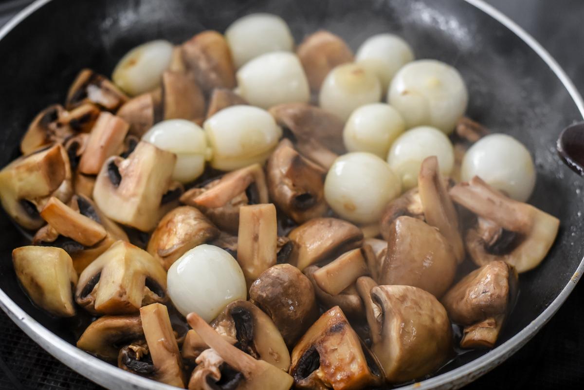 While the chicken is in the oven, cook the mushrooms and pearl onions. (Audrey Le Goff)