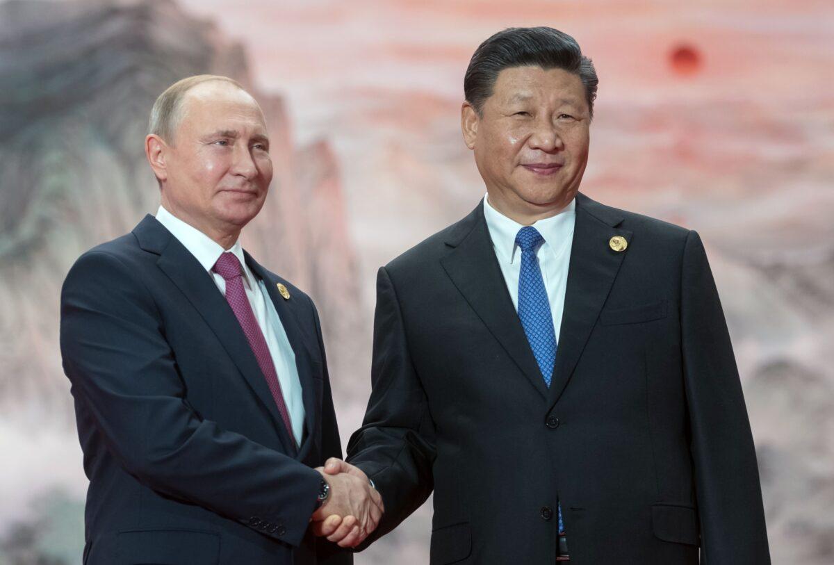  Russian President Vladimir Putin (l) shakes hands with President of the Peoples Republic of China Xi Jinping during a welcoming ceremony at the Shanghai Cooperation Organization (SCO) Council of Heads of State in Qingdao, China, on June 10, 2018. (Sergei Guneyev/Sputnik/AFP via Getty Images)