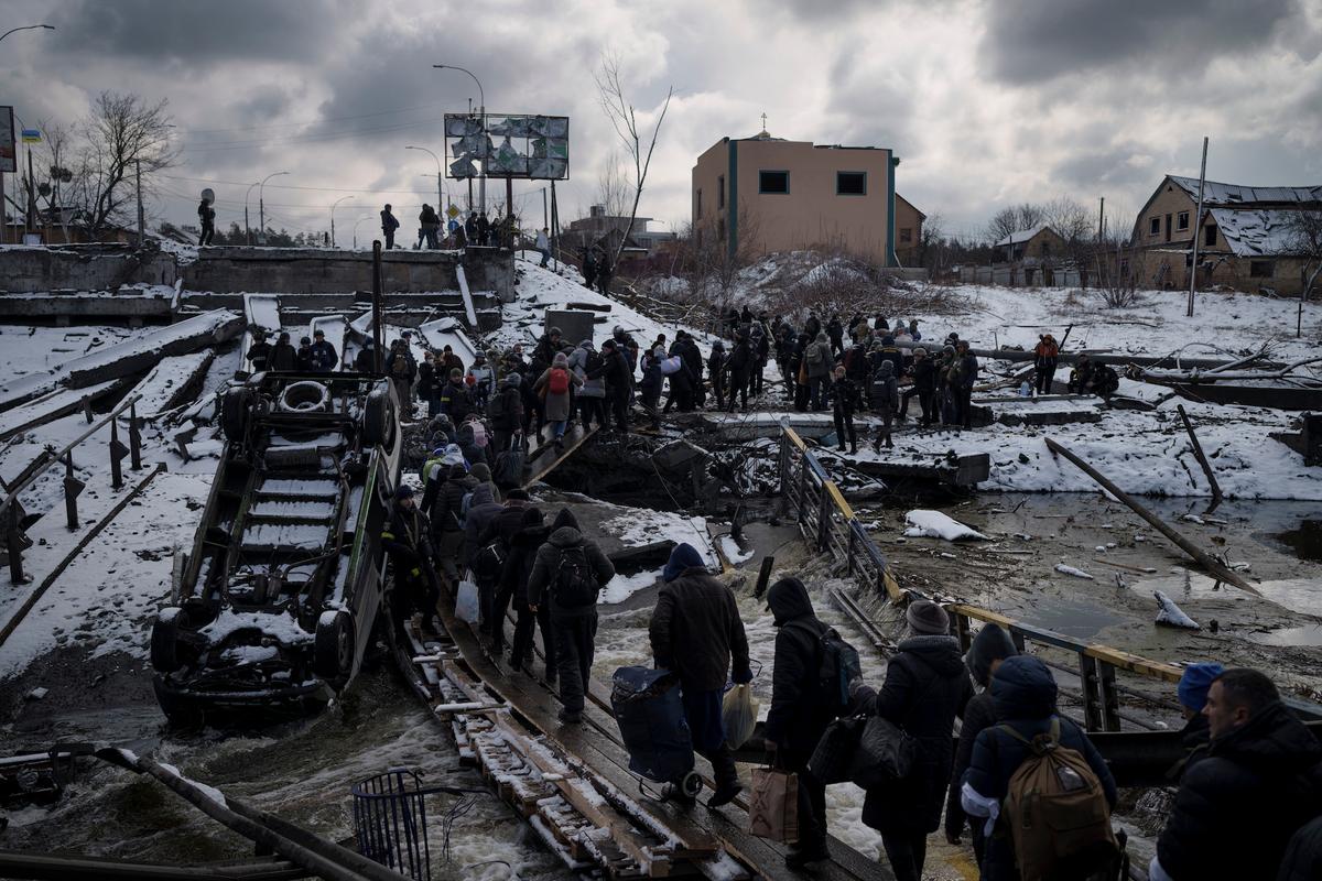 Ukrainians cross an improvised path under a destroyed bridge while fleeing Irpin, in the outskirts of Kyiv, Ukraine, on March 8, 2022. (Felipe Dana/AP Photo)