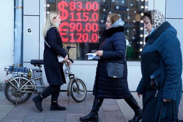 People walk past a currency exchange office screen displaying the exchange rates of the U.S. dollar and the euro to Russian rubles in Moscow on Feb. 28, 2022. (Pavel Golovkin, File/AP Photo)