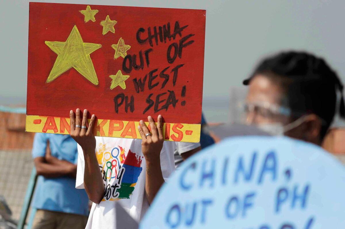Activists hold up signs against a recently passed Chinese Coast Guard law during a rally in Manila, Philippines, on Feb. 24, 2021. The Philippine government summoned the Chinese ambassador on March 14, 2022, to protest what it said was the “illegal incursion” of a Chinese navy ship into the country’s waters for three days and demanded China to order its ships to respect the country’s territory and follow international law, officials said. (Aaron Favila/AP Photo)