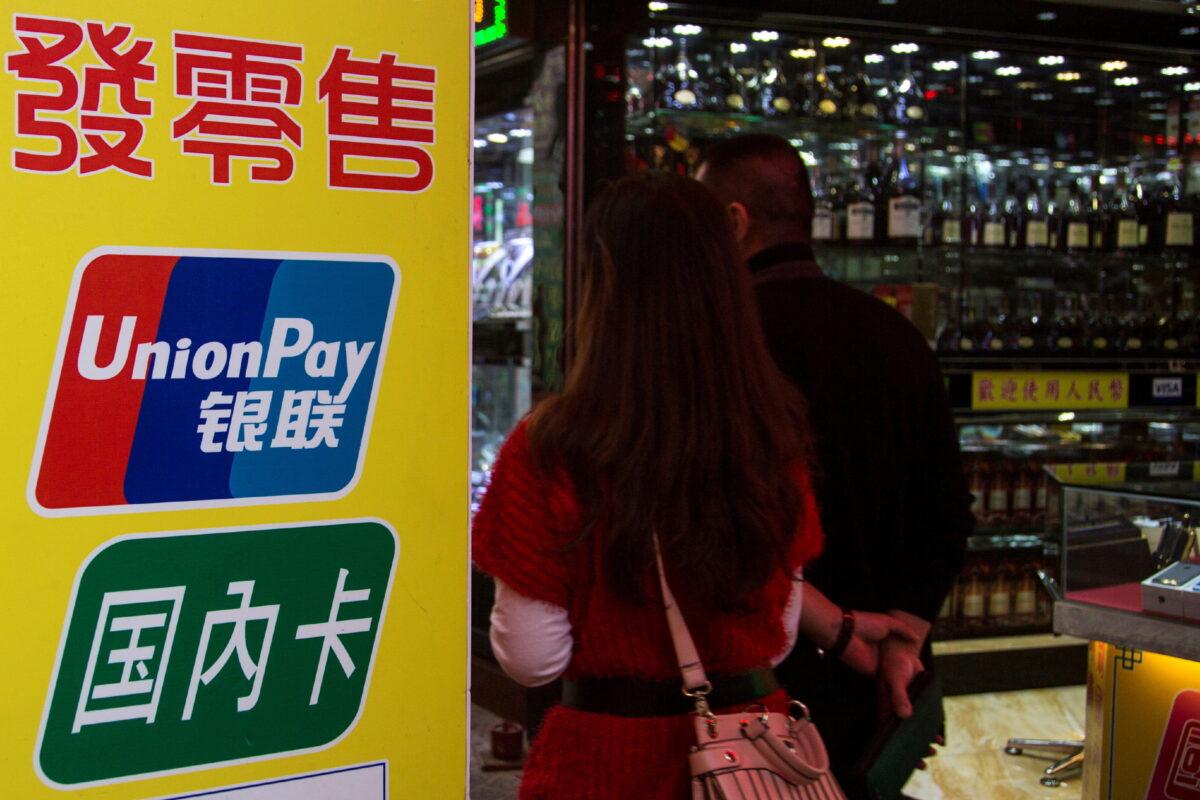 Chinese visitors walk past a sign for China UnionPay outside a pawn shop in Macau on Nov. 20, 2013. (Tyrone Siu/Reuters)