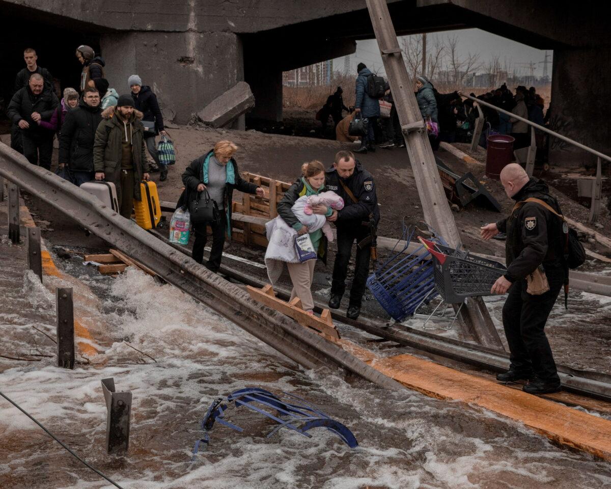 Local residents cross a destroyed bridge as they evacuate from their town in Irpin, near Kyiv, Ukraine, on March 7, 2022. (Jedrzej Nowicki/Agencja Wyborcza.pl via Reuters)