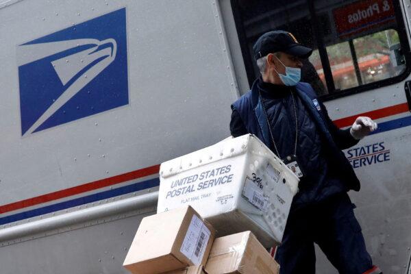 A United States Postal Service (USPS) worker unloads packages from his truck in Manhattan, New York on April 13, 2020. (Mike Segar/Reuters)
