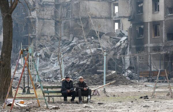 Local residents sit on a bench near an apartment building destroyed in the course of the Ukraine–Russia conflict in the besieged southern port city of Mariupol, Ukraine, on March 25, 2022. (Alexander Ermochenko/Reuters)