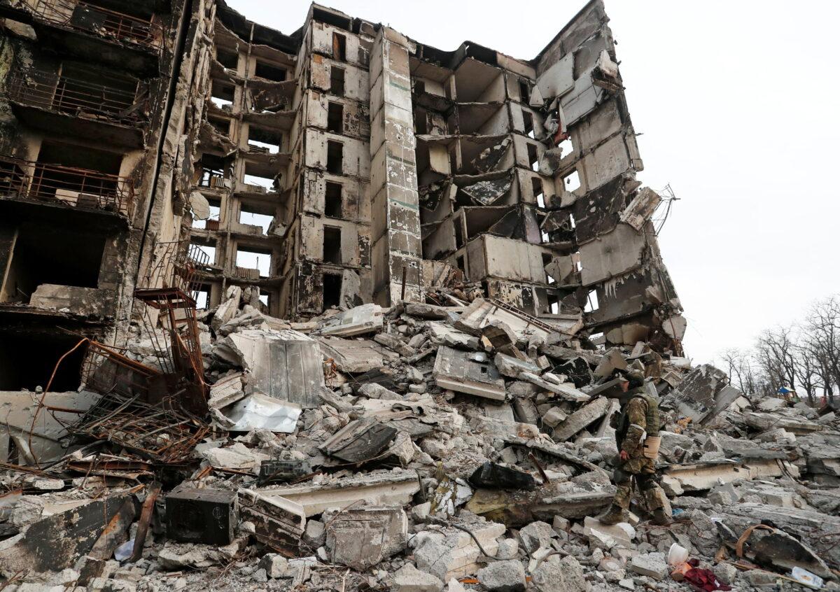 A service member of pro-Russian troops stands on the ruins of a destroyed apartment building in Mariupol, Ukraine, on March 30, 2022. (Alexander Ermochenko/Reuters)
