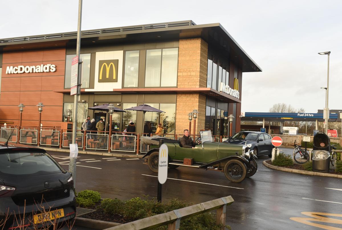 Mark and his 1931 Alvis driving by a McDonald's. (Courtesy of Caters News)