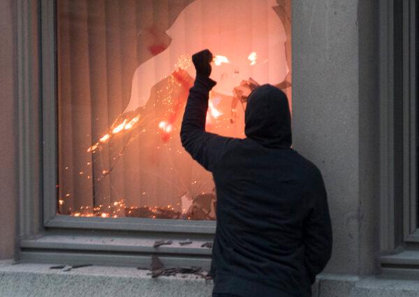 A protester puts a flare through a window in Montreal during a demonstration of the death of George Floyd by police in Minneapolis, on May 31, 2020. (The Canadian Press/Graham Hughes)