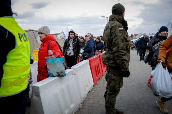 A Polish soldier helps direct Ukrainian refugees waiting for a bus after they arrived in Poland through the Medyka border crossing on March 10, 2022. (Charlotte Cuthbertson/The Epoch Times)