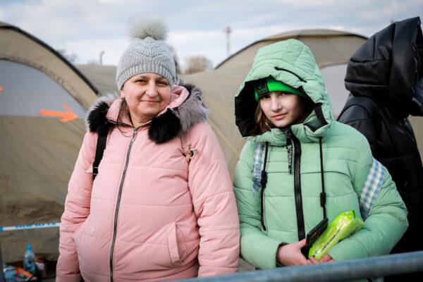 Ukrainian refugees Olena Sayenko and her daughter Kristina wait for a bus after arriving in Poland through the Medyka border crossing on March 10, 2022. (Charlotte Cuthbertson/The Epoch Times)