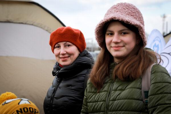 Ukrainian refugees Lena Yegorova and her daughter Polina Yegorova wait for a bus heading further west after arriving in Poland through the Medyka border crossing on March 10, 2022. (Charlotte Cuthbertson/The Epoch Times)