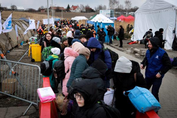 Ukrainian refugees wait for a bus heading further west after arriving in Poland through the Medyka border crossing on March 10, 2022. (Charlotte Cuthbertson/The Epoch Times)