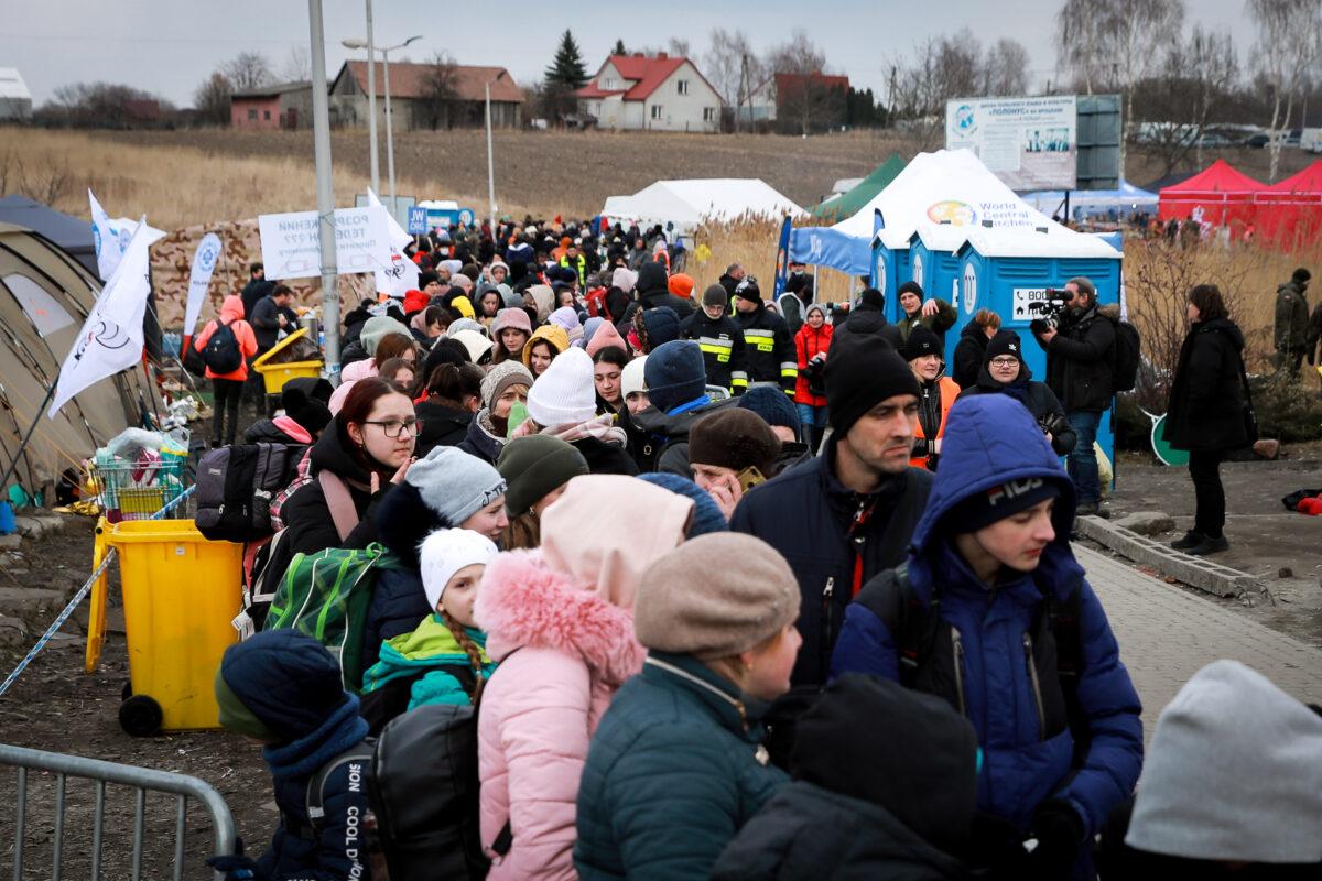 Ukrainian refugees wait for a bus heading further west after arriving in Poland through the Medyka border crossing on March 10, 2022. (Charlotte Cuthbertson/The Epoch Times)
