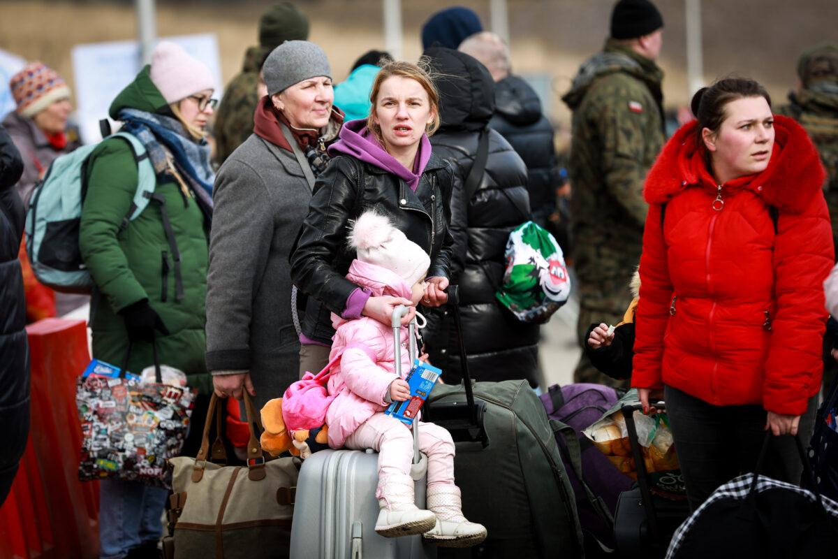 Ukrainian refugees walk into Poland through the Medyka border crossing on March 10, 2022. (Charlotte Cuthbertson/The Epoch Times)