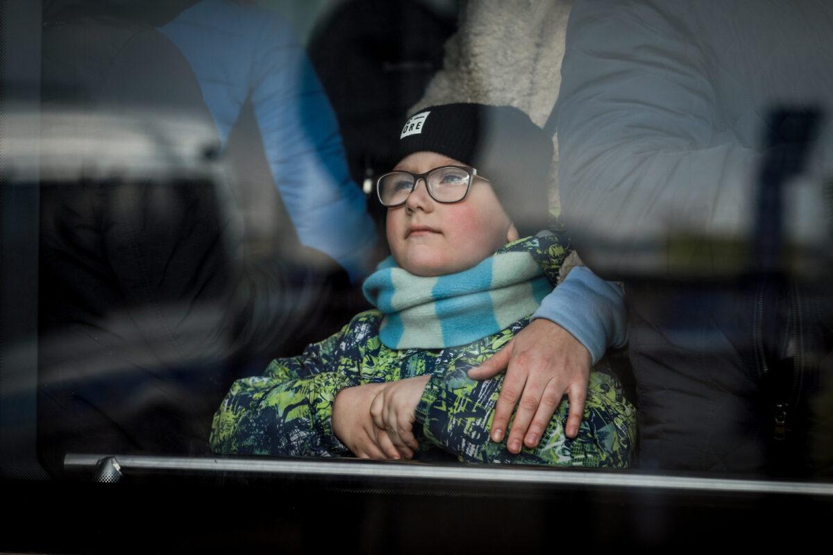 A Ukrainian refugee boy looks out a bus window after arriving in Poland through the Medyka border crossing on March 10, 2022. (Charlotte Cuthbertson/The Epoch Times)