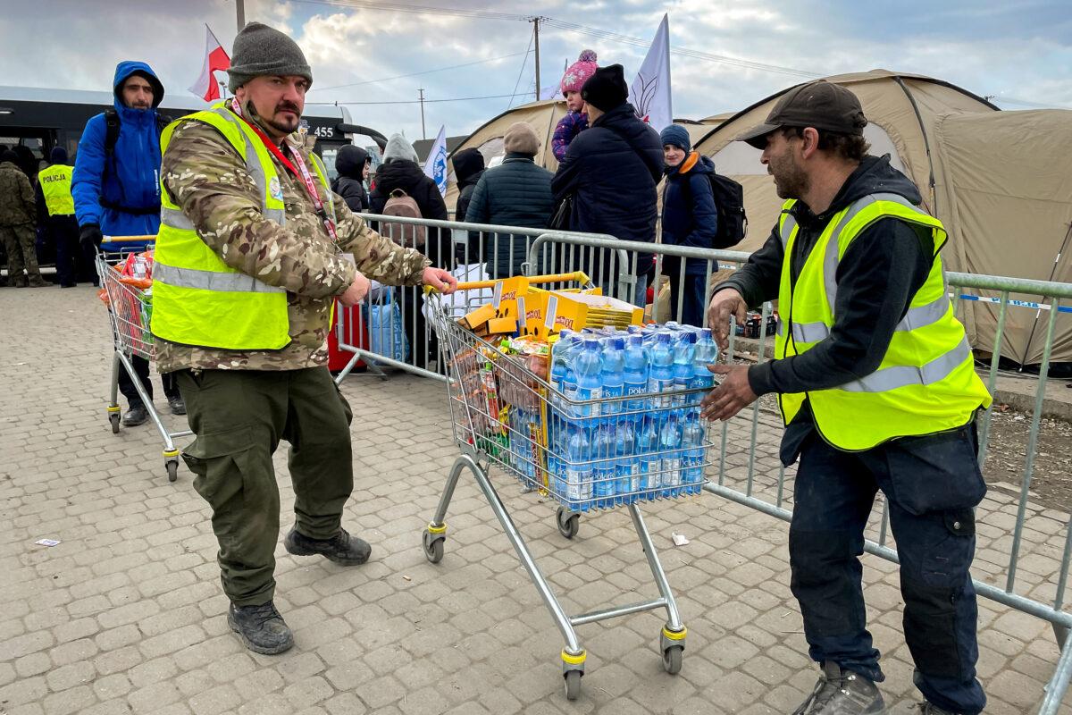 Volunteers load shopping carts full of food and water to wheel into Ukraine for those waiting to cross into Poland through the Medyka border crossing on March 10, 2022. (Charlotte Cuthbertson/The Epoch Times)