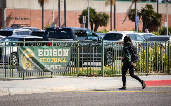 A student walks past a sign for the school's football team at Edison High School in Huntington Beach, Calif., on March 10, 2022. (John Fredricks/The Epoch Times)
