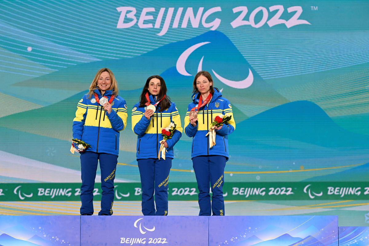 Gold medallist Iryna Bui of Team Ukraine (C), Silver medallist Oleksandra Kononova of Team Ukraine (L), and Bronze medallist Liudmyla Liashenko of Team Ukraine (R) celebrate during the Women's Para Biathlon Middle Distance Standing medal ceremony at the Zhangjiakou Medals Plaza on day four of the Beijing 2022 Winter Paralympics in Zhangjiakou, China, on March 8, 2022. (Zhe Ji/Getty Images for International Paralympic Committee)