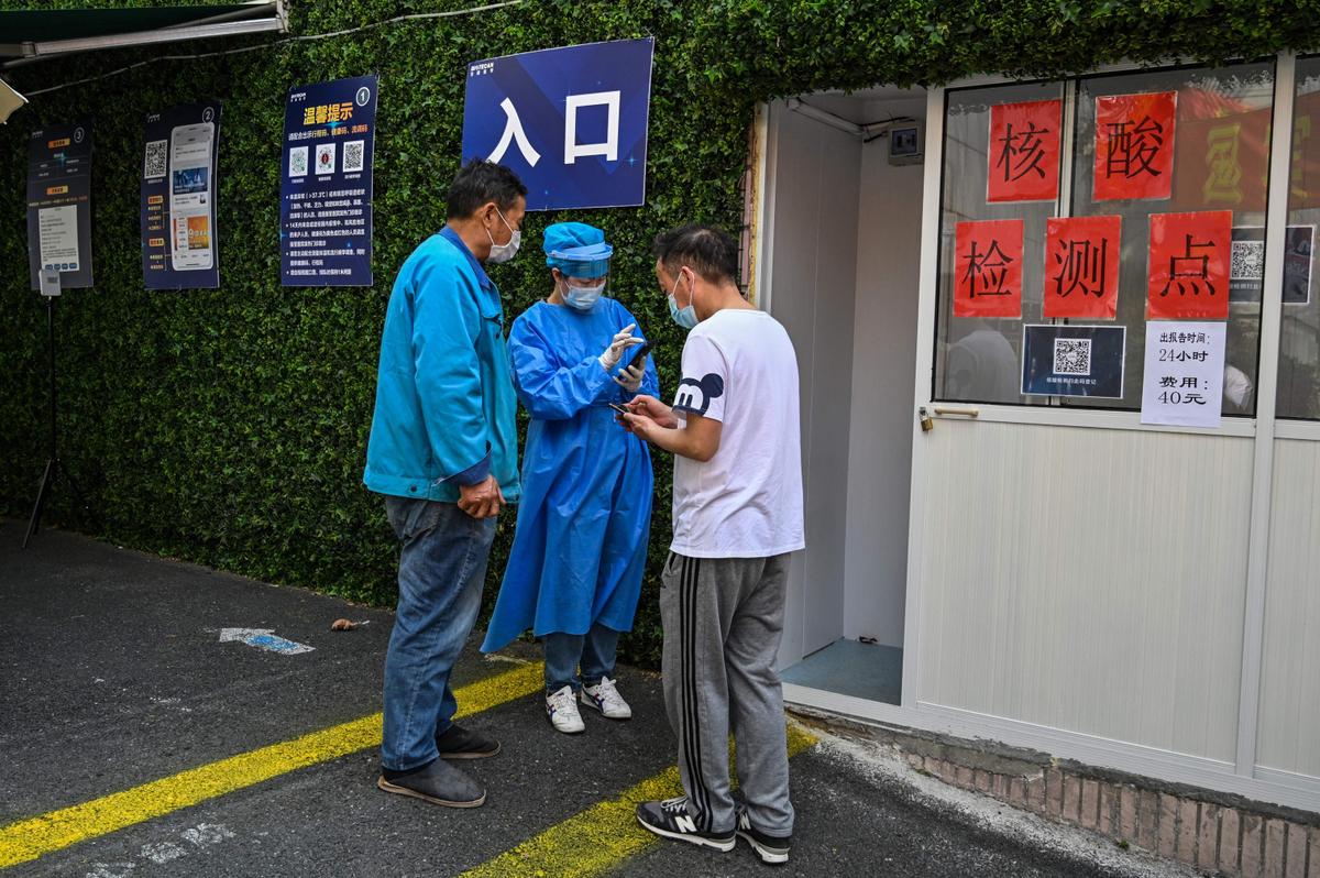 A health worker (C) helps people to fill out information requested in an app to be able to be tested as a measure against COVID-19 near the Shanghai Jin'an Central Hospital, in Shanghai on March 14, 2022. (Hector Retamal/AFP via Getty Images)