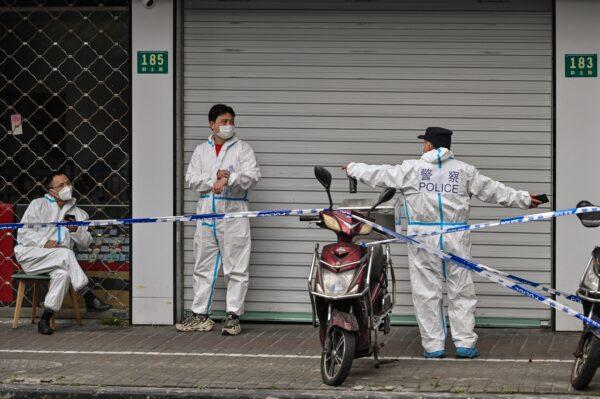 Police and workers are seen wearing protective clothes next to some lockdown areas after the detection of new cases of COVID-19 in Shanghai on March 14, 2022. (Hector Retamal/AFP via Getty Images)