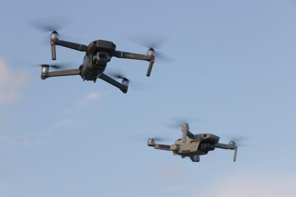 A DJI Mavic 2 Pro and DJi Mavic Mini made by the Chinese drone maker fly near each other in Miami, Florida on Dec. 15, 2021. (Joe Raedle/Getty Images)