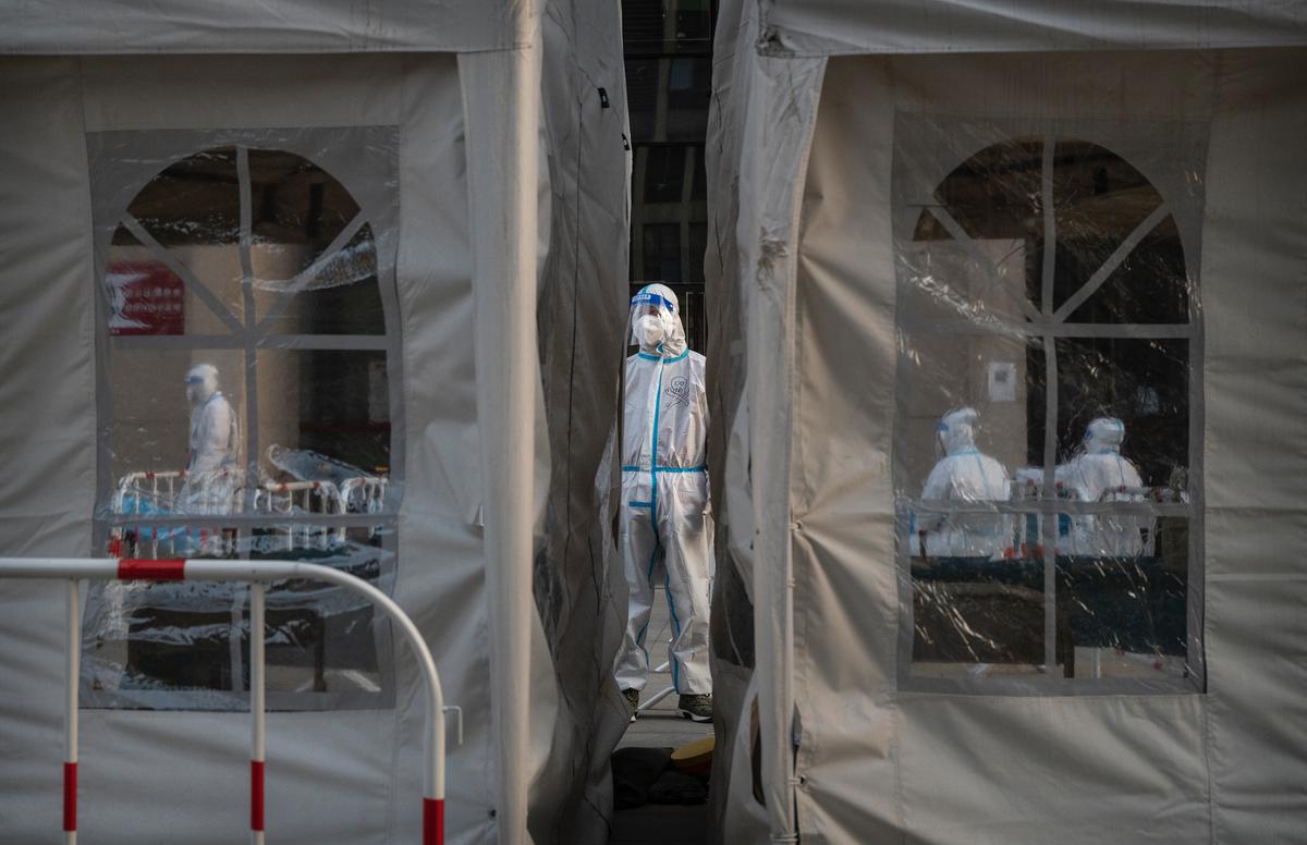 A health worker dressed in protective clothing waits to assist people at a mass COVID-19 testing site in Beijing on March 14, 2022. (Kevin Frayer/Getty Images)