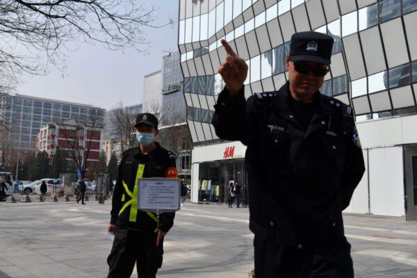 A policeman tries to prevent photos being taken outside a store of Swedish clothing giant H&M in Beijing, on March 25, 2021. H&M faced calls for a boycott as a backlash brews against Western firms speaking out on human rights. (Greg Baker/AFP via Getty Images)
