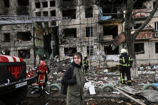 A citizen stands near firefighters in front of a destroyed apartment building after it was shelled in the northwestern Obolon district of Kyiv, Ukraine on March 14, 2022. (Aris Messinis/AFP via Getty Images)