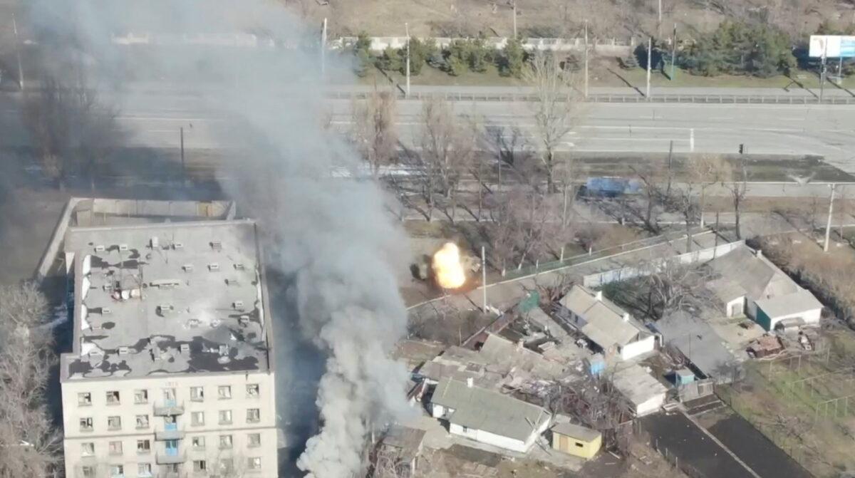 An aerial view shows smoke rising as an armored vehicle is shot next to a building, as Russia's invasion of Ukraine continues, in Mariupol, Ukraine, as uploaded in this handout drone video obtained by Reuters on March 13, 2022. (Azov Mariupol/Handout via Reuters)