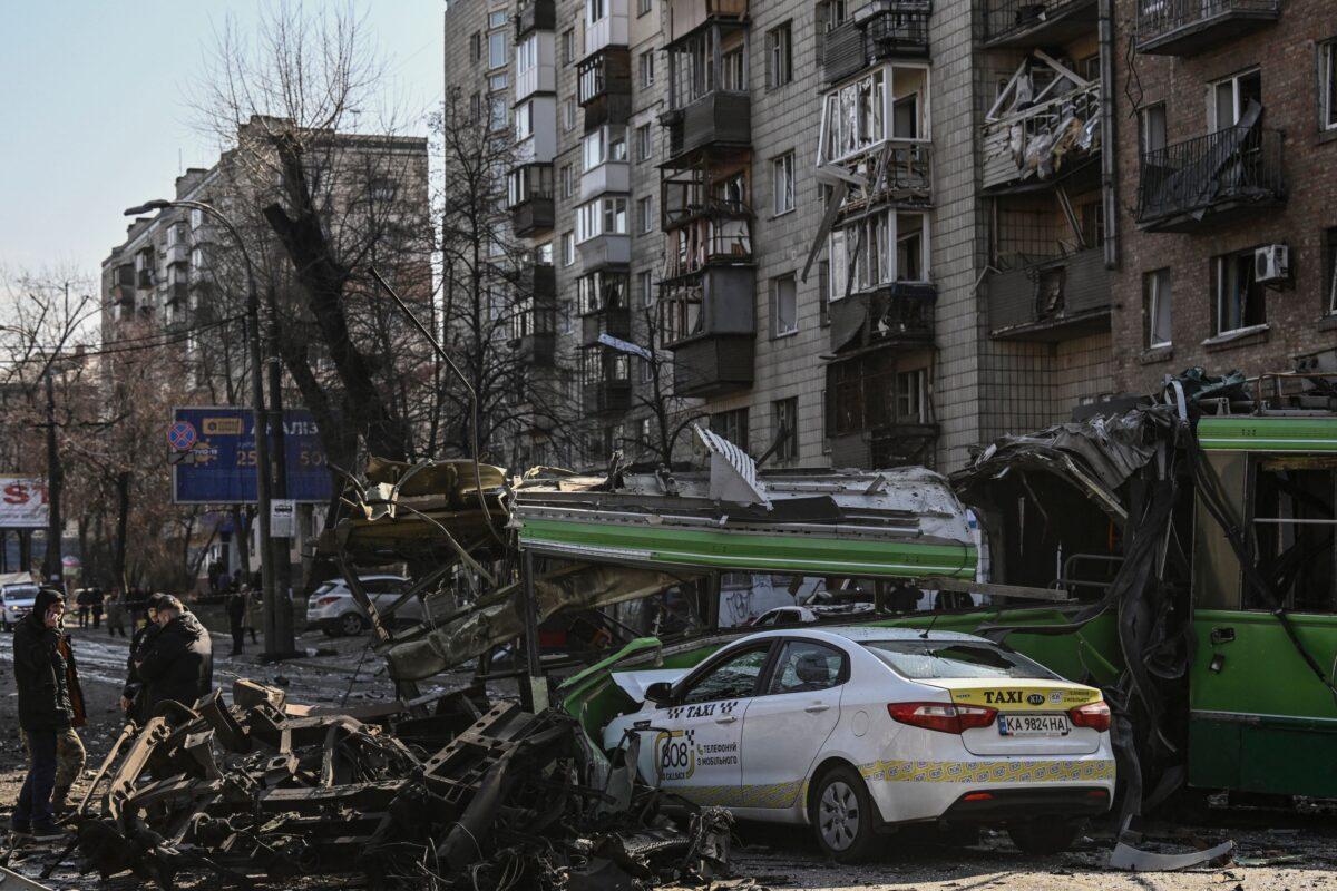 A Ukranian serviceman (L) walks in front of a destroyed apartment building after it was shelled in Kyiv, Ukraine, on March 14, 2022. (Aris Messinis/AFP via Getty Images)