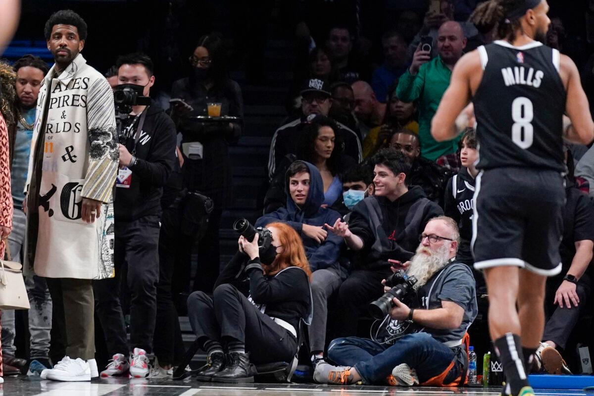 Brooklyn Nets' Kyrie Irving, left, looks over the court as he enters the arena during the first half of the NBA basketball game between the Brooklyn Nets and the New York Knicks at the Barclays Center in New York City on March 13, 2022. (Seth Wenig/AP Photo)
