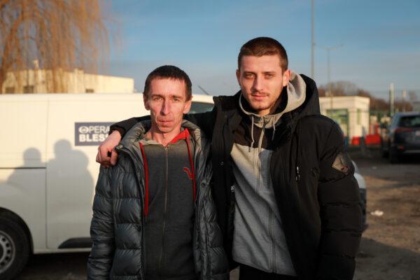 Ukrainians Roman Medvedev (L) and his stepson, Vladimir Shevchuk, who are traveling from Poland to Ukraine to join the civilian force, stand in Medyka, Poland, next to a border crossing on March 12, 2022. (Charlotte Cuthbertson/The Epoch Times)