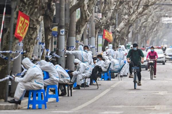 Workers are seen wearing protective gear next to a lockdown area after the detection of new cases of covid-19 in Shanghai on March 14, 2022. (Hector Retamal/AFP via Getty Images)