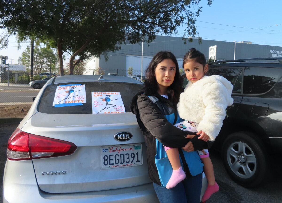 Khaterine Cote and her daughter joined a protest outside an Amazon warehouse and Uber Greenlight hub in Redondo Beach, Calif., on March 16, 2022. (Alice Sun/The Epoch Times)