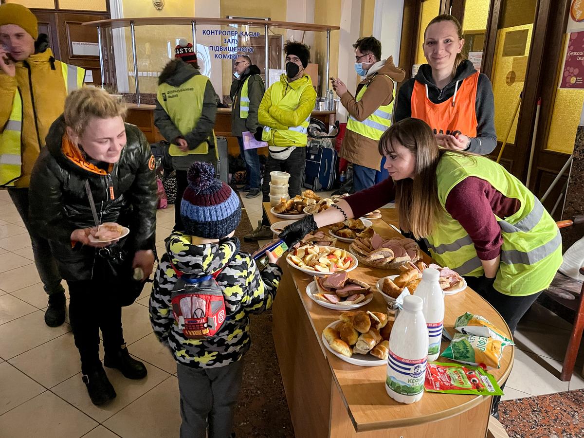 A boy is handed a snack as his mother watches at the Lviv train station in western Ukraine, on March 16, 2022. (Charlotte Cuthbertson/The Epoch Times)
