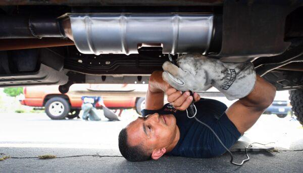 Deputy Jaime Moran from the Los Angeles Sheriffs Department engraves the catalytic converter of a vehicle with a traceable number, in City of Industry, Calif., on July 14, 2021. (Frederic J. Brown/AFP via Getty Images)