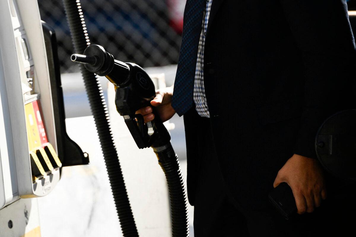 A customer returns a nozzle to a pump after fueling gasoline into a sport utility vehicle (SUV) at a Shell gas station in the Chinatown neighborhood of Los Angeles, Calif., on Feb. 17, 2022. (Patrick T. Fallon/AFP via Getty Images)