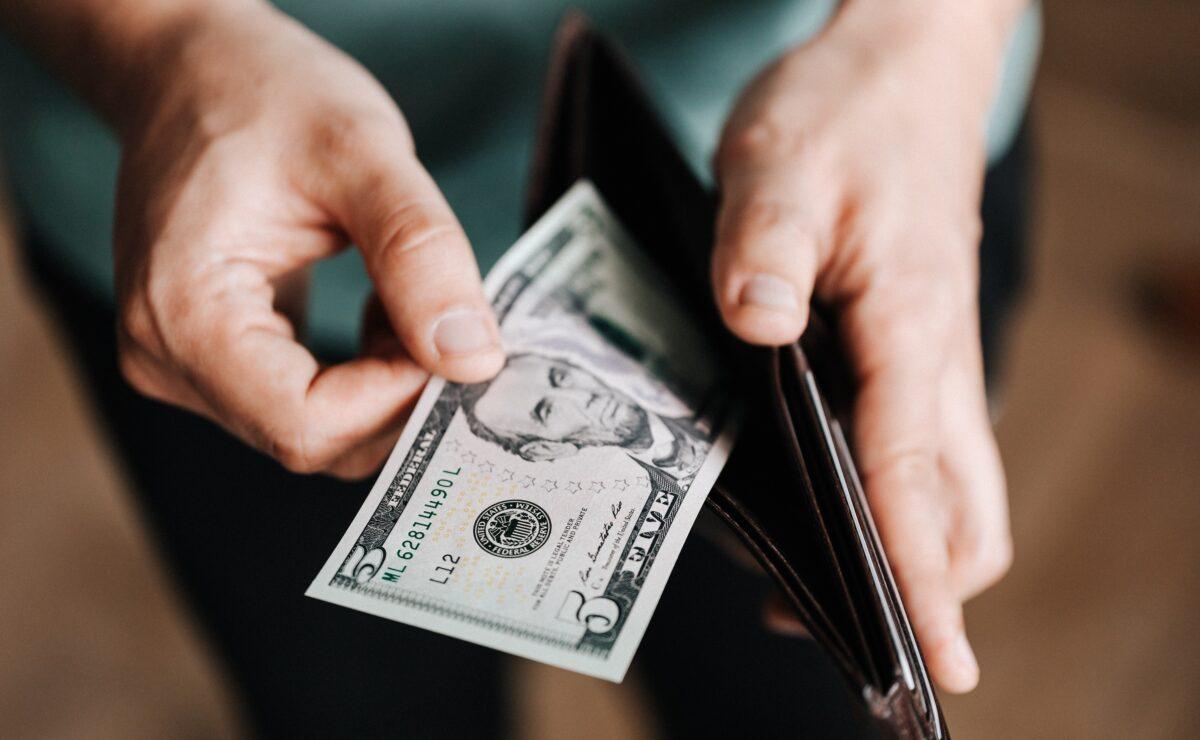 Stock photo of a person holding a wallet with dollar notes. (Karolina Grabowska/Pexels)