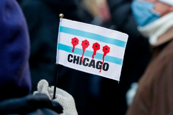 A woman holds a small flag depicting bloody bullet holes during an anti-gun-violence march on the Magnificent Mile in Chicago, on Dec. 31, 2020. (Kamil Krzaczynski/AFP via Getty Images)