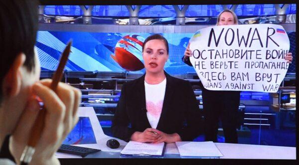 An image of Russian Channel One employee Marina Ovsyannikova entering Ostankino on-air TV studio in Moscow during Russia's most-watched evening news broadcast on March 14, holding up a poster that reads as "No War" and condemning Moscow's military action in Ukraine, taken on March 15, 2022. (AFP via Getty Images)