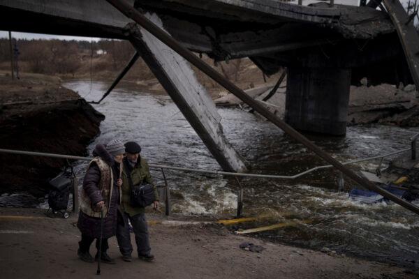 Elderly residents cross a destroyed bridge while fleeing Irpin, on the outskirts of Kyiv, Ukraine on March 13, 2022. (Felipe Dana/AP Photo)