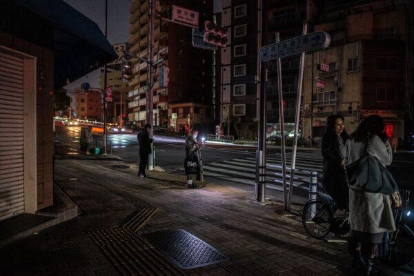 People along a street of a residential area during a power outage in Koto district in Tokyo early on March 17, 2022, after a powerful 7.4-magnitude quake jolted eastern Japan. (Philip Fong/AFP via Getty Images)