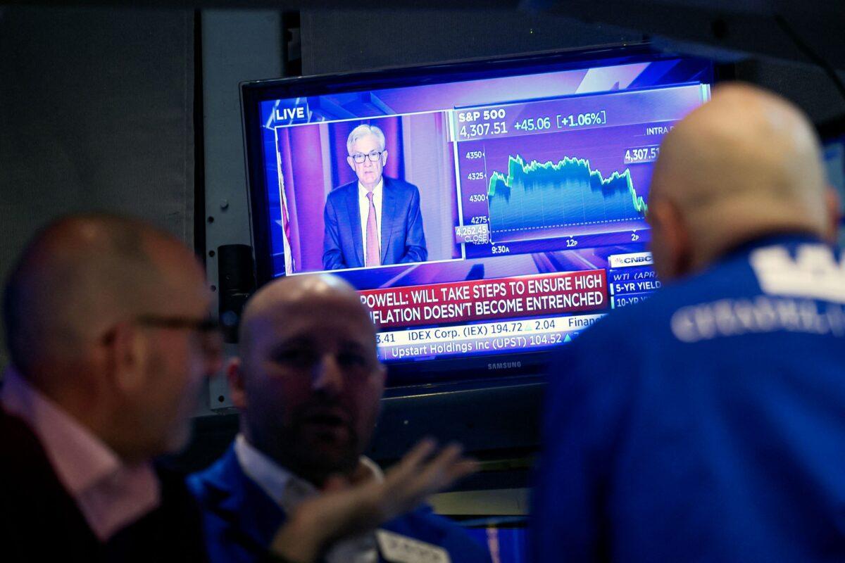 Traders work, as Federal Reserve Chair Jerome Powell is seen on a screen delivering remarks, at the New York Stock Exchange in New York, on March 16, 2022. (Brendan McDermid/Reuters)